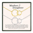a necklace with two interlocking circular pendants, representing the bond between a mother and daughter. The necklace is displayed in a box, and there is accompanying text that describes the necklace as a special bond that spans the years, built on trust, love, and shared experiences.