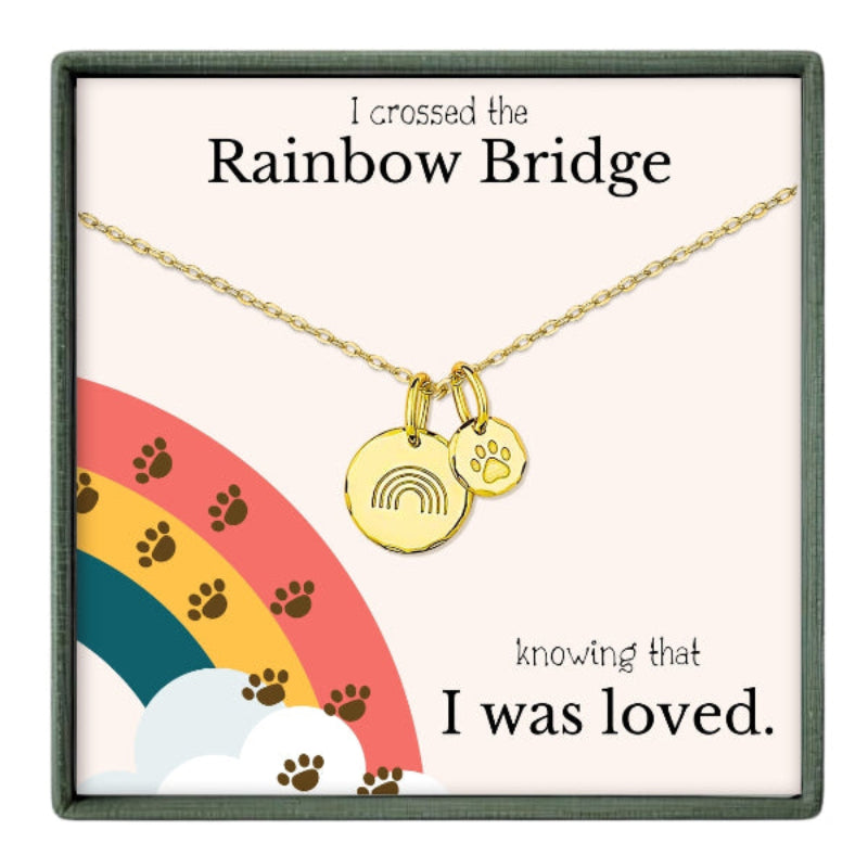 The image is a necklace with a charm that says "I crossed the Rainbow Bridge" and a paw print charm, accompanied by the text "knowing that I was loved."