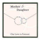 a necklace with two circular pendants, and it is presented in a square frame with a pink background.