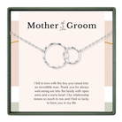 The image is a necklace with two interlocking silver rings, and it is presented in a square frame with a pink background.