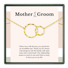 The image is a necklace with two gold-colored circular pendants, and it is presented in a square frame with a pink background.