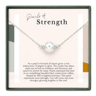 a necklace with a pearl pendant, which is described as a symbol of strength and resilience.