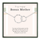 The image is a gift box containing a silver necklace with two interlocking circular pendants. The box is labeled "to my amazing Bonus Mother" and includes a message expressing gratitude for the gift of life and love.