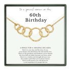 The image is a birthday gift box with a gold necklace featuring a series of rings. The text on the gift box reads "to a special woman on her 60th Birthday" and provides a message about the rings symbolizing the person's life experiences and the positive qualities they have shared.