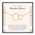 a necklace with two circular pendants, and there is a message written in black text above the necklace.