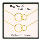 a set of two gold-colored necklaces with interlocking circular pendants, accompanied by the text "Big Sis & Little Sis" and "Our Love is Forever."