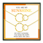The image is a necklace set with two gold-colored circular pendants, accompanied by a message that reads "You are my sunshine. My only sunshine, you make me happy when skies are grey."