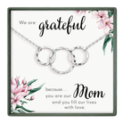 A necklace with three interlocking rings, accompanied by a floral design and a message expressing gratitude and love for a mother.