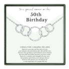 The image is a birthday gift box with a silver necklace featuring a unique design of five rings. The text on the gift box reads "to a special woman on her 50th Birthday" and provides a message about the recipient's life, including their past, present, and future.