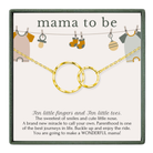 The image is a gift card for a baby shower, featuring a necklace with two gold rings and baby clothes hanging on a clothesline.