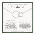 The image is a memorial tribute to a beloved husband, featuring a necklace with two interlocking rings and a heartfelt message about the love and memories shared between the couple.