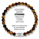 A beaded bracelet with brown and black beads, and a stainless steel pipe with the words 'HONEST', 'KIND', 'STRONG', 'BRAVE', 'WISE', 'LOYAL' engraved. The bracelet is described as a reflection of the incredible person the wearer is.